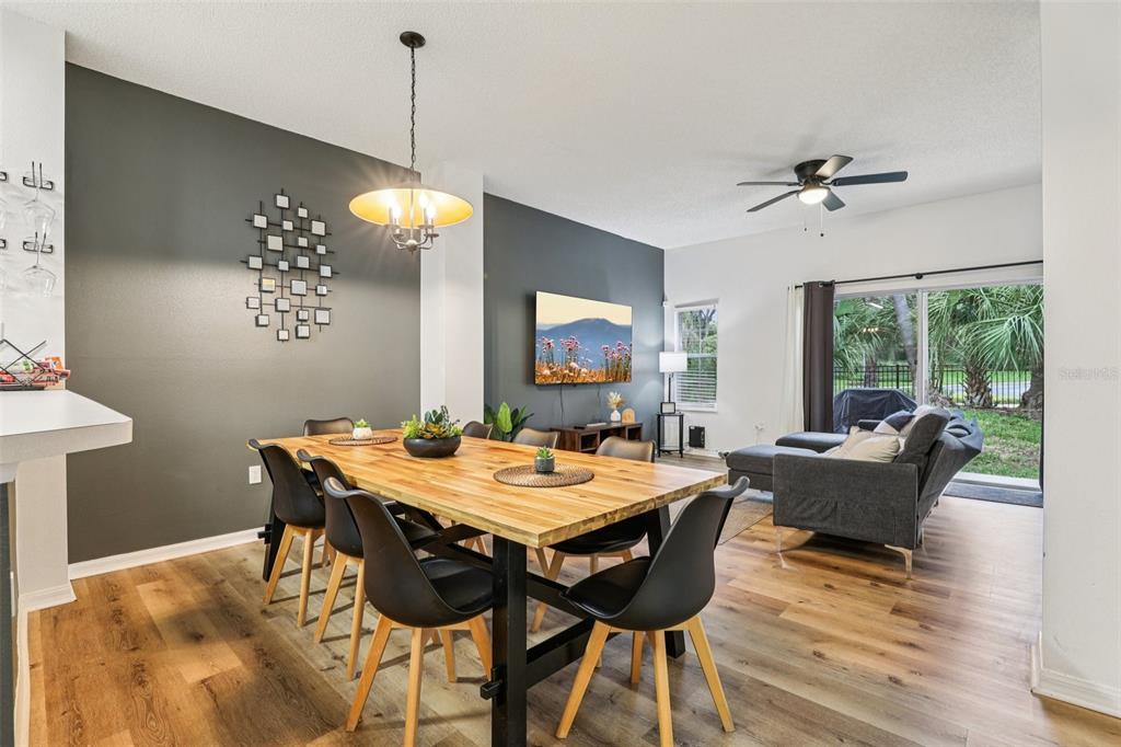 A dining area with a wooden table and black chairs sits before a living room — 8419 CRYSTAL COVE LOOP, KISSIMMEE, FL