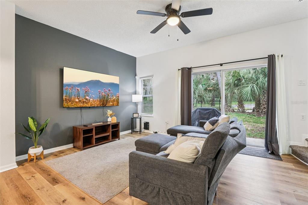 A living room features a dark gray accent wall, a sectional sofa, and sliding glass doors — 8419 CRYSTAL COVE LOOP, KISSIMMEE, FL