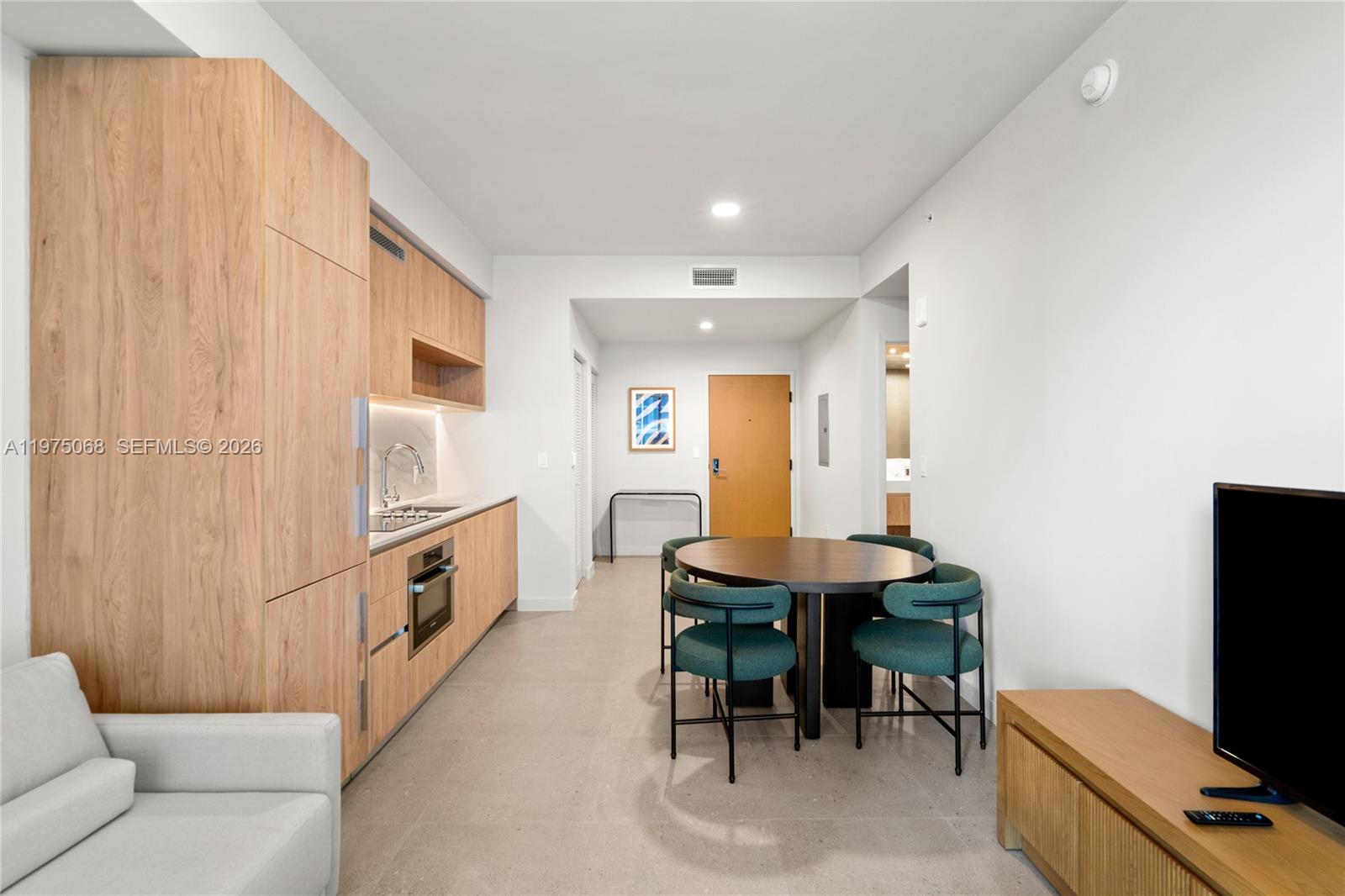A modern studio apartment features a kitchenette with light wood cabinetry and a dining area — 11 NE 6th St # 2104, Miami FL 33132, MIAMI, FL