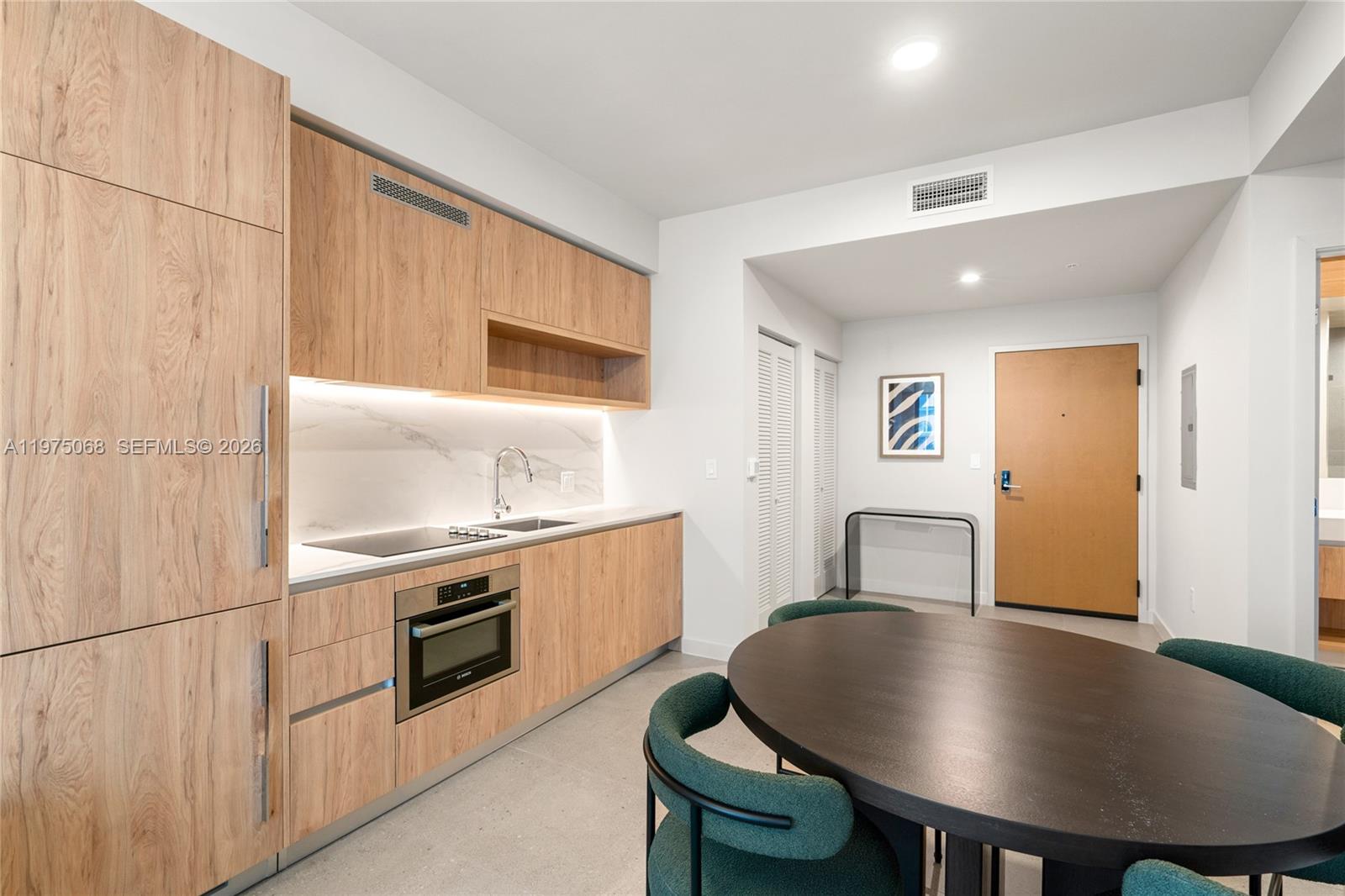 A modern kitchen features light wood cabinetry, a marble backsplash, and a dark dining table — 11 NE 6th St # 2104, Miami FL 33132, MIAMI, FL