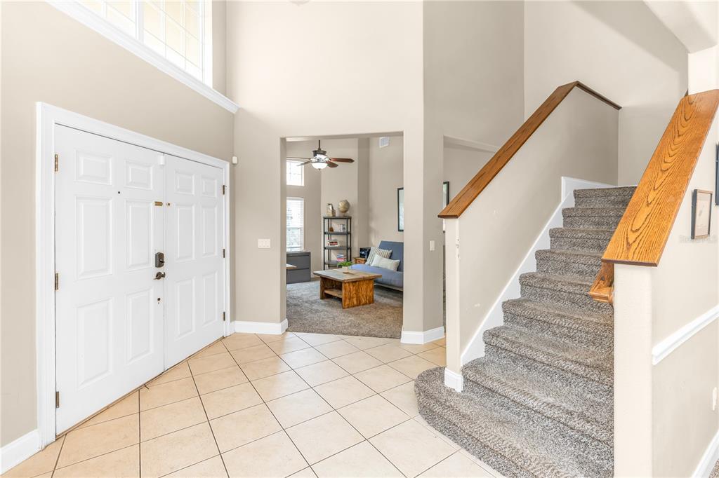 An entryway features a tiled floor, a carpeted staircase with a wooden railing, and a doorway — 6971 LUCCA STREET, ORLANDO, FL