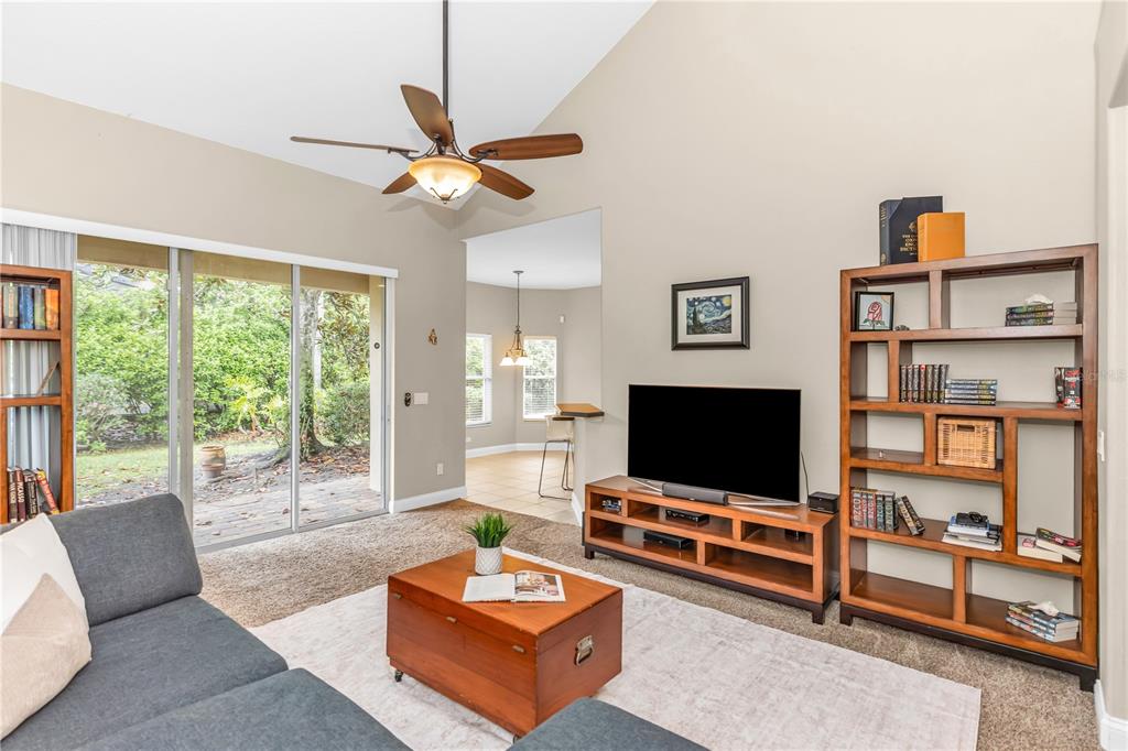 A living room with vaulted ceilings, a ceiling fan, carpet, and a wooden bookshelf — 6971 LUCCA STREET, ORLANDO, FL