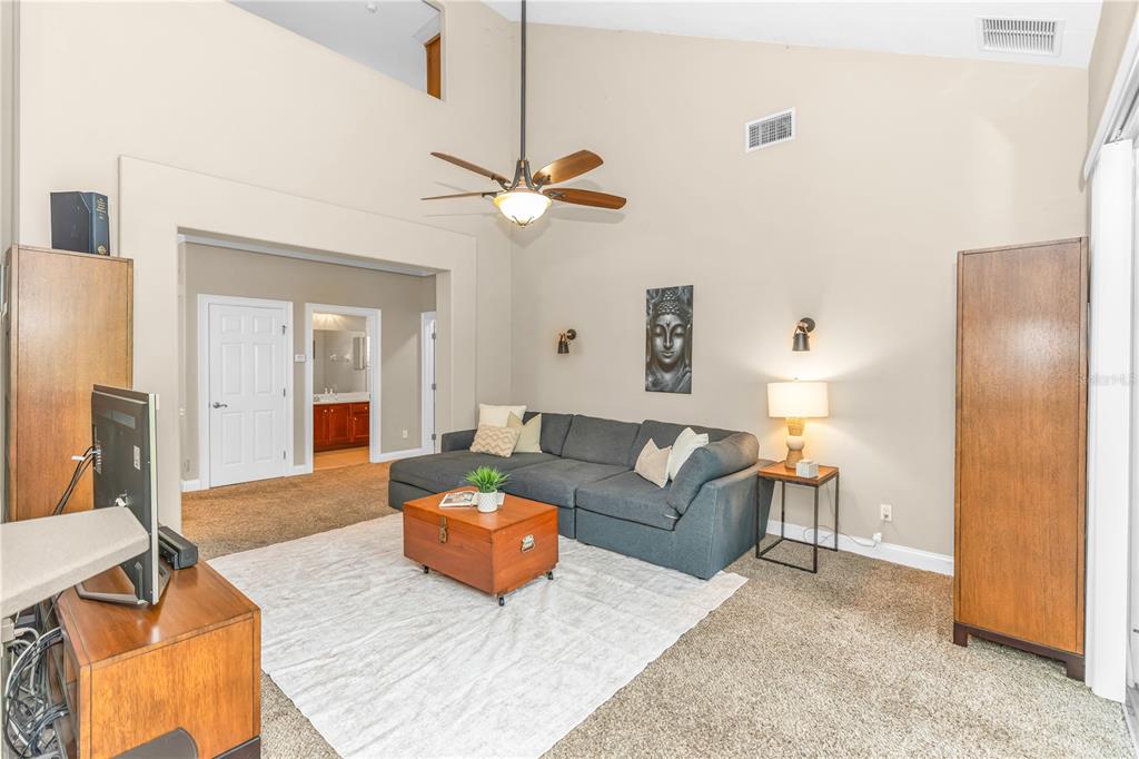 A living room with a vaulted ceiling, a gray sectional sofa, and a wooden coffee table — 6971 LUCCA STREET, ORLANDO, FL