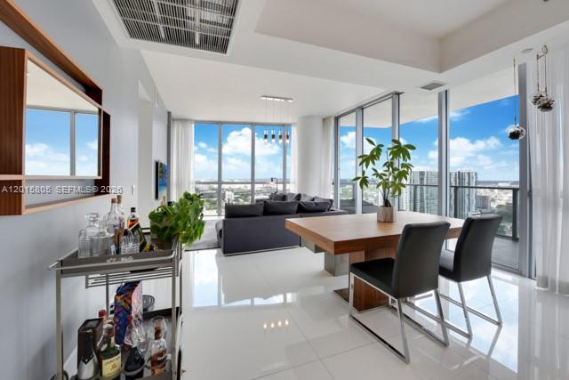 A modern dining area features a wooden table, black chairs, and a bar cart — 1100 Biscayne Blvd # 3205, Miami FL 33132, MIAMI, FL