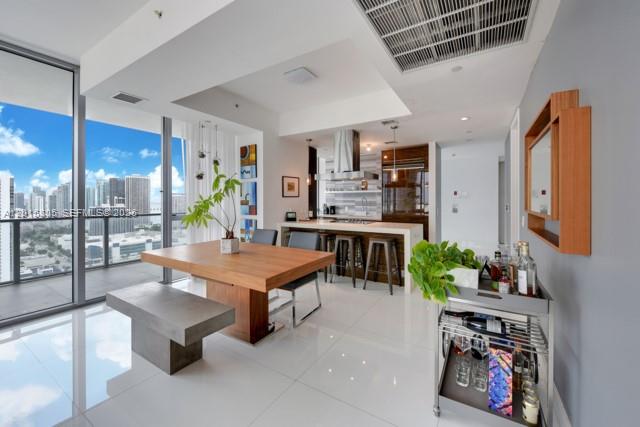 A modern dining area features a wooden table, bench seating, and a nearby bar cart — 1100 Biscayne Blvd # 3205, Miami FL 33132, MIAMI, FL