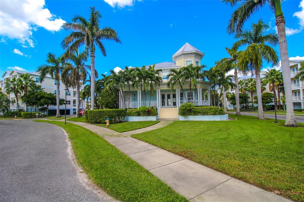 A light blue two-story building with a tower and palm trees on a sunny day — 7710 34TH AVENUE W UNIT 101, BRADENTON, FL