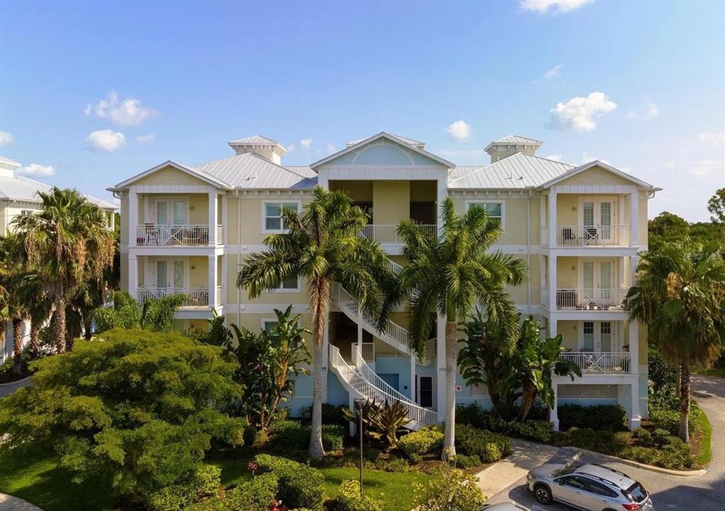 A three-story apartment building with light yellow siding, white trim, and exterior staircases — 7710 34TH AVENUE W UNIT 101, BRADENTON, FL