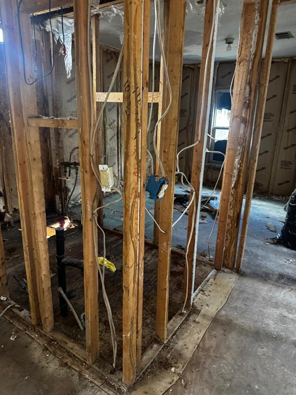 An interior view of a room under renovation showing exposed wooden wall studs and wiring — 2626 SHINER DRIVE, LAKE WALES, FL