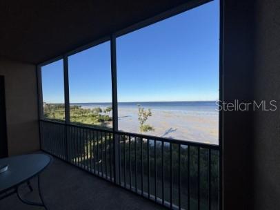 A screened-in balcony overlooks a sandy beach and the ocean under a clear blue sky — 8542 VIVANTE BOULEVARD, PUNTA GORDA, FL