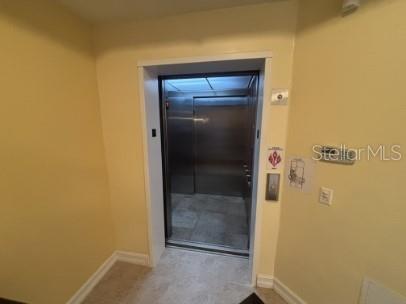 An open elevator door reveals a stainless steel interior in a room with yellow walls — 8542 VIVANTE BOULEVARD, PUNTA GORDA, FL