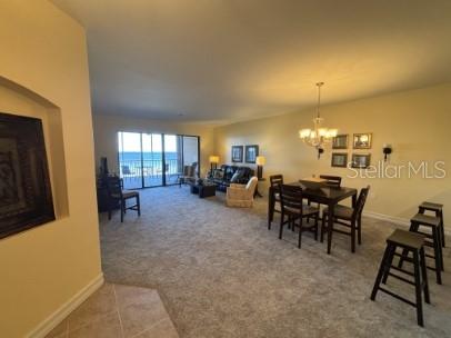 An open-concept living and dining area features carpeted floors, a balcony, and a chandelier — 8542 VIVANTE BOULEVARD, PUNTA GORDA, FL