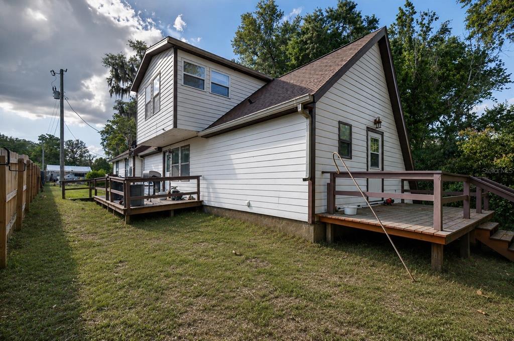 A two-story house with white siding and wooden decks in a grassy backyard — 14953 SE 107TH AVENUE, SUMMERFIELD, FL