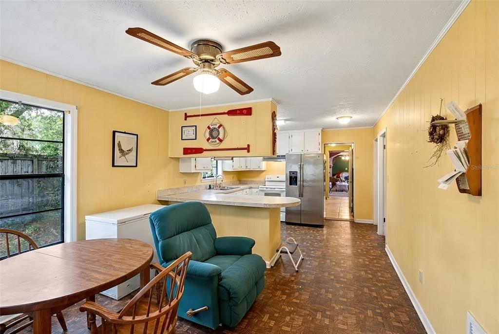 A kitchen and dining area with yellow walls, wood-look flooring, and a teal recliner — 14953 SE 107TH AVENUE, SUMMERFIELD, FL