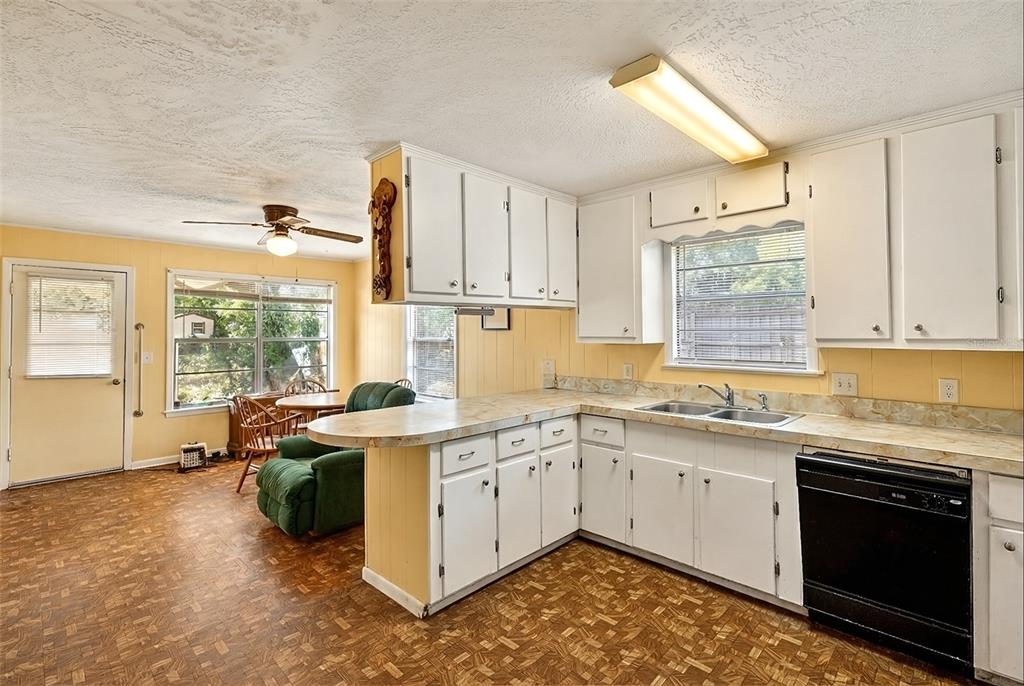 A kitchen with white cabinets, a laminate countertop, and a black dishwasher on patterned flooring — 14953 SE 107TH AVENUE, SUMMERFIELD, FL