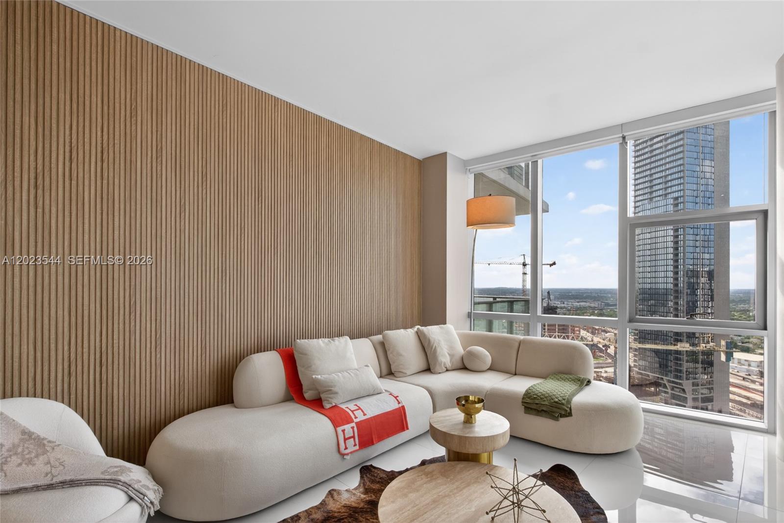 A modern living room features a curved cream sofa against a vertical wood slat wall — 851 NE 1st Ave # 3201, Miami FL 33132, MIAMI, FL