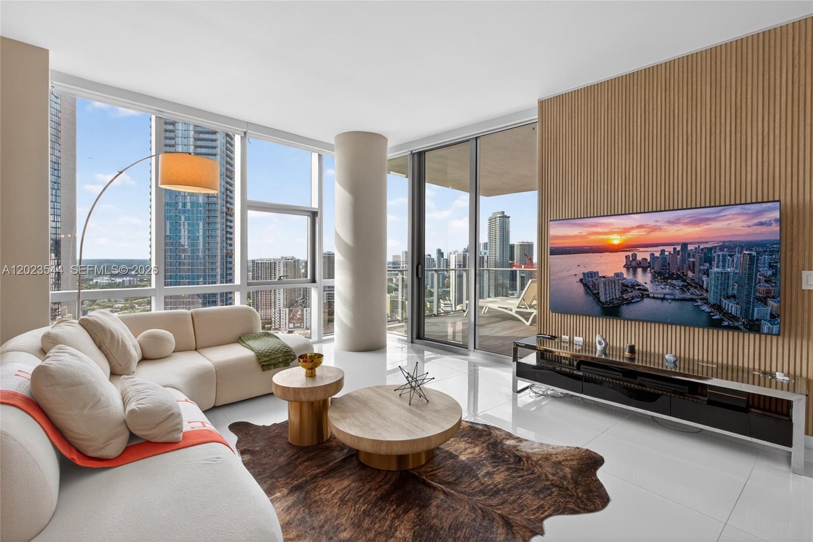 A modern living room features floor-to-ceiling windows, a wood-slat accent wall, and city views — 851 NE 1st Ave # 3201, Miami FL 33132, MIAMI, FL