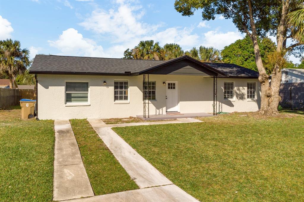 A single-story house with a light-colored stucco exterior, a dark roof, and a concrete driveway — 140 JUAREZ DRIVE, KISSIMMEE, FL