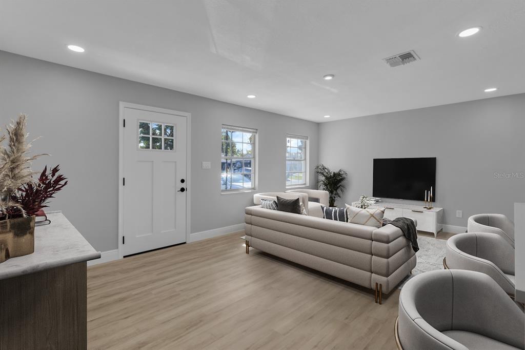 A living room features light wood-look flooring, gray walls, recessed lighting, and a white door — 140 JUAREZ DRIVE, KISSIMMEE, FL