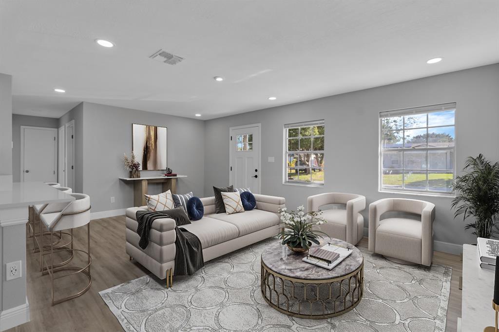 A living room features light gray walls, wood-look flooring, a sofa, two armchairs, and barstools — 140 JUAREZ DRIVE, KISSIMMEE, FL