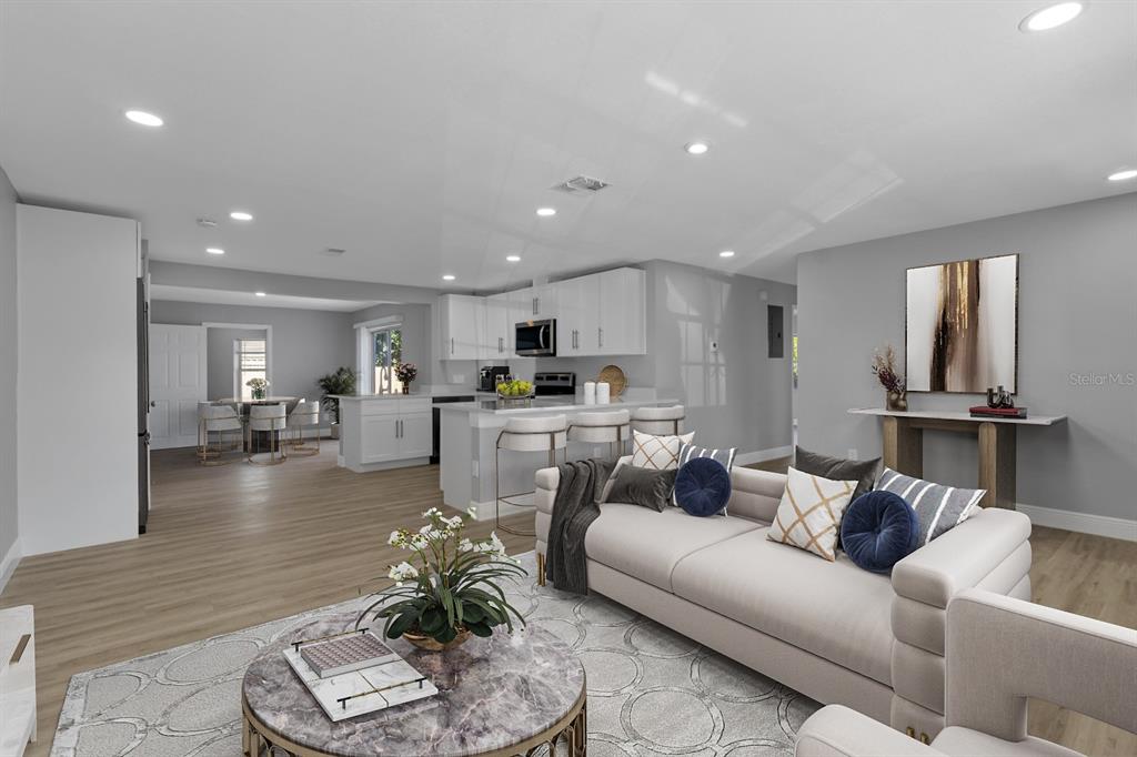 An open-concept living room and kitchen featuring light wood floors, white cabinetry, and modern furniture — 140 JUAREZ DRIVE, KISSIMMEE, FL