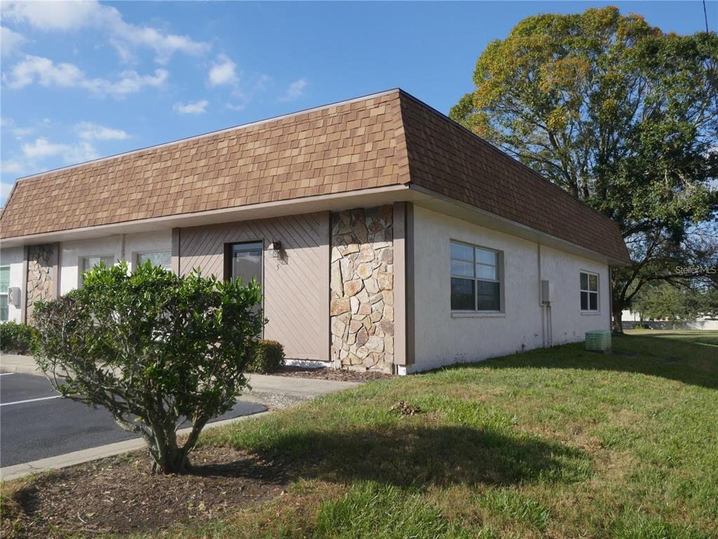 A single-story commercial building features a mansard roof, stone accents, and a paved parking area — 6165 CHESHAM DRIVE UNIT 5, NEW PORT RICHEY, FL