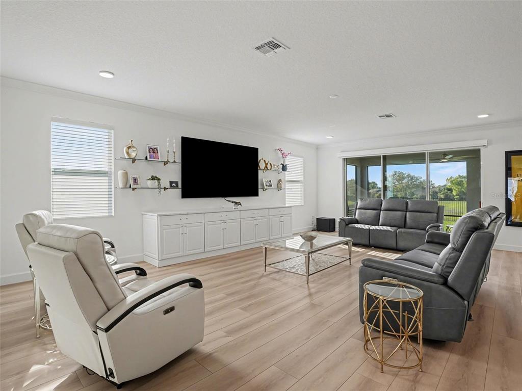 A bright living room features light wood floors, white cabinetry, and grey leather seating — 2612 RAVENCLIFFE TERRACE, OVIEDO, FL