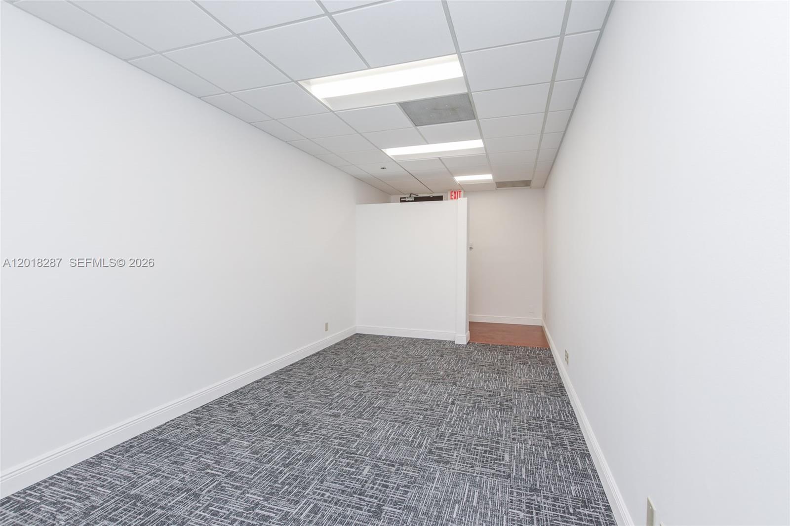 An empty office space features white walls, a gray patterned carpet, and a drop ceiling — 1900 Glades Rd # 357, Boca Raton FL 33431, BOCA RATON, FL