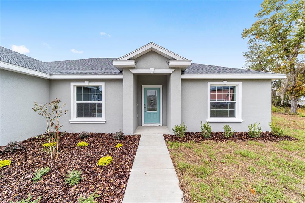 A single-story gray house with a light blue front door and a concrete walkway — 4190 SW 98TH STREET, OCALA, FL