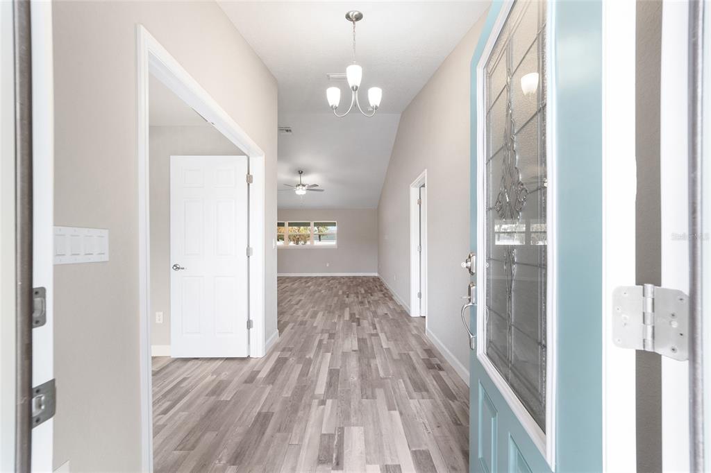 A view from an open front door into a hallway with wood-look flooring — 4190 SW 98TH STREET, OCALA, FL