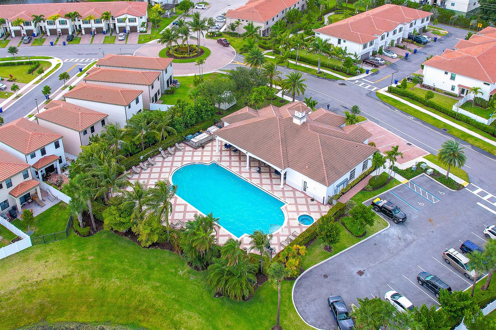 An aerial view of a community clubhouse featuring a swimming pool, spa, and parking lot — 2024 Sugar Maple Drive, Riviera Beach FL 33410, RIVIERA BEACH, FL