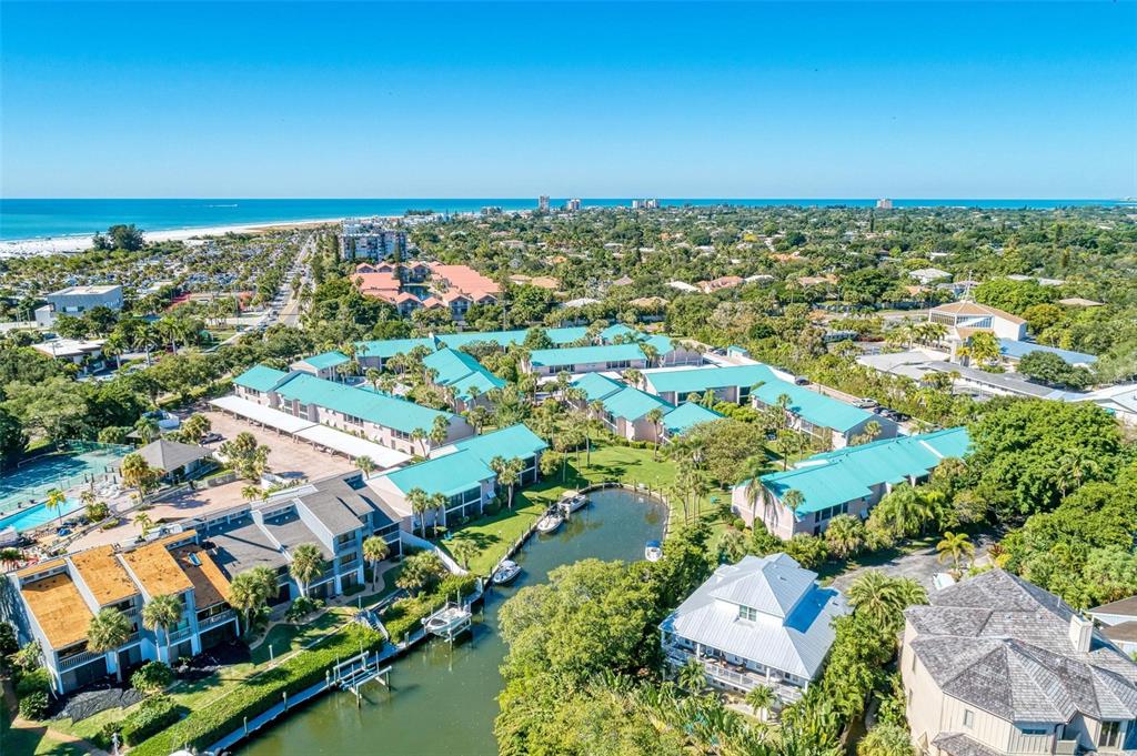Aerial view of a waterfront residential complex with teal roofs and a canal — 5683 MIDNIGHT PASS ROAD UNIT 105, SARASOTA, FL