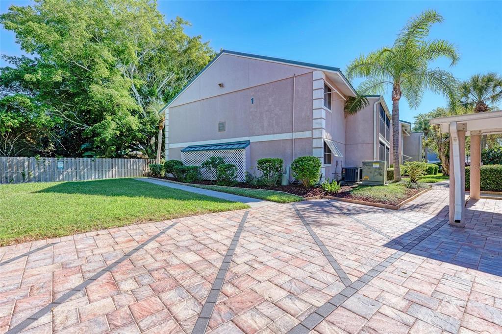 A two-story pink stucco building with a paved patio and a palm tree — 5683 MIDNIGHT PASS ROAD UNIT 105, SARASOTA, FL