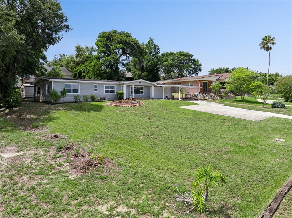 A single-story house with light gray siding, a carport, and a large front lawn — 1024 SUNSET DRIVE, LAKE WALES, FL