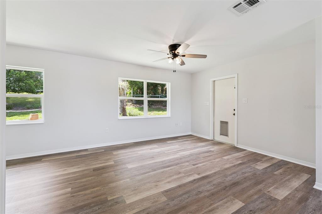 An empty room with light gray walls, wood-look flooring, a ceiling fan, and two windows — 1024 SUNSET DRIVE, LAKE WALES, FL