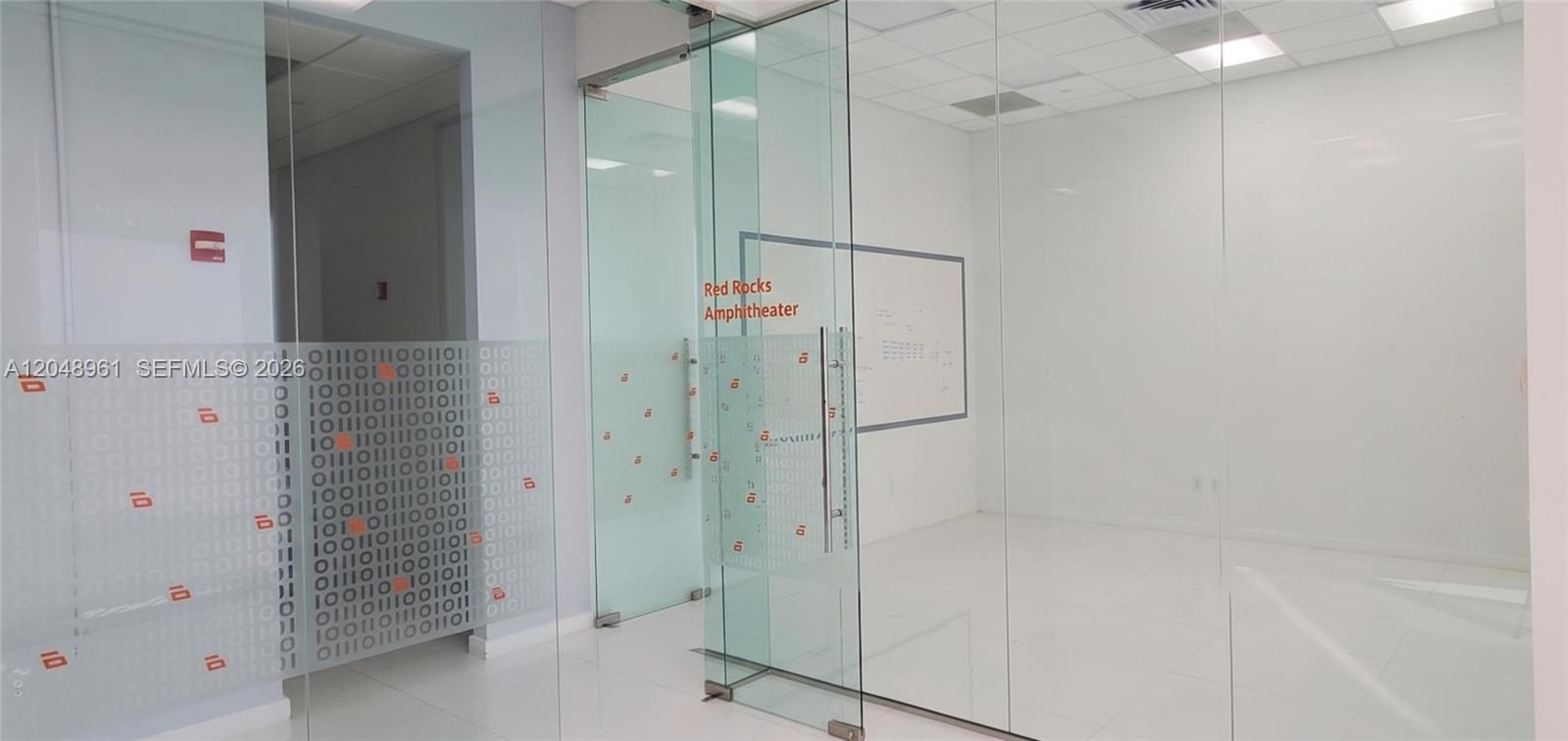 A modern office space features glass walls, white tiled floors, and binary code window decals — 1200 Brickell Ave # 200C, Miami FL 33131, MIAMI, FL