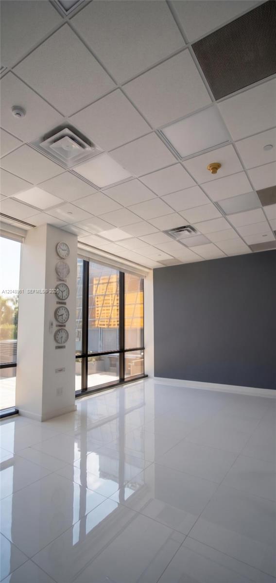 An empty office space features white tile floors, a drop ceiling, and a dark accent wall — 1200 Brickell Ave # 200C, Miami FL 33131, MIAMI, FL
