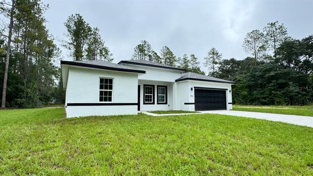 A single-story white house with black trim and a black garage door sits on grass — 2456 W MAGENTA DRIVE, CITRUS SPRINGS, FL