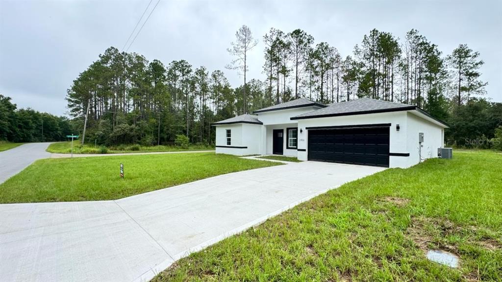 A modern white single-story house with a black garage door and a concrete driveway — 2456 W MAGENTA DRIVE, CITRUS SPRINGS, FL