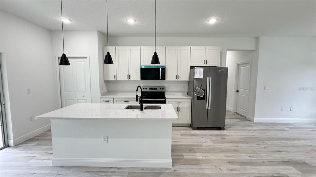 A modern kitchen features white cabinets, stainless steel appliances, and a large quartz-topped island — 2456 W MAGENTA DRIVE, CITRUS SPRINGS, FL