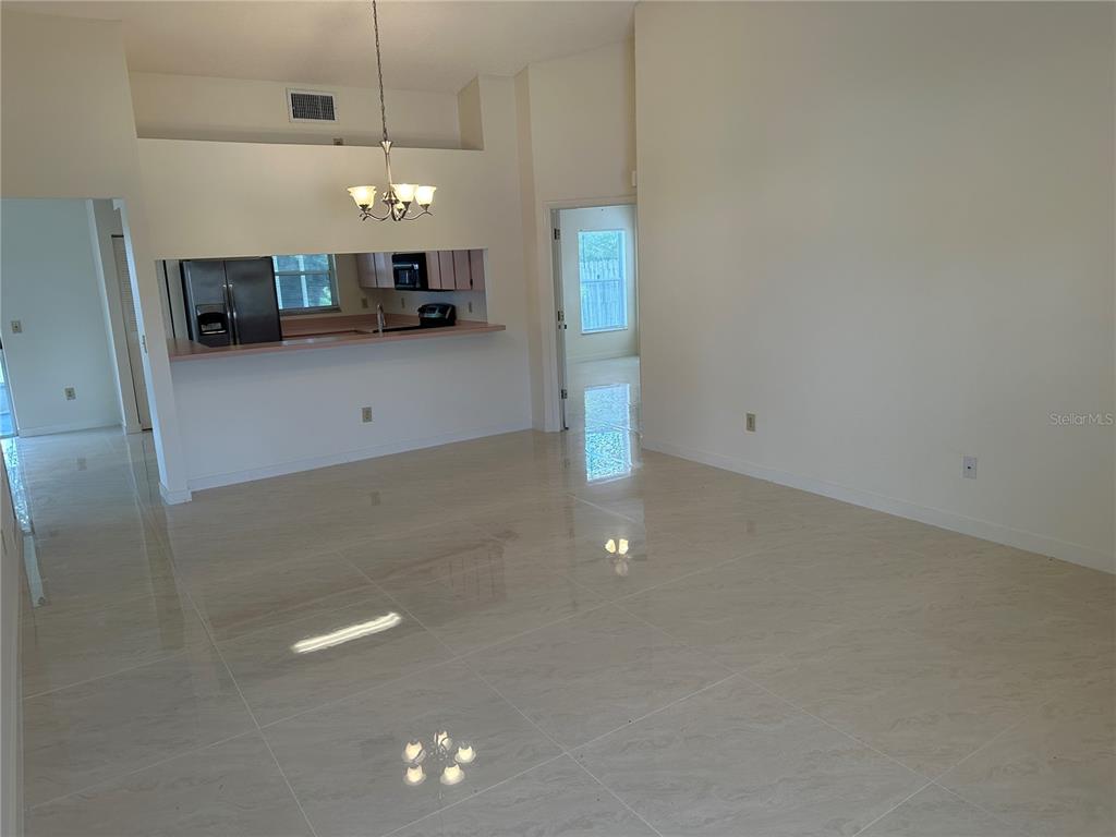 A living area with light tile flooring opens to a kitchen with a breakfast bar — 5915 TAYWOOD DRIVE, TAMPA, FL