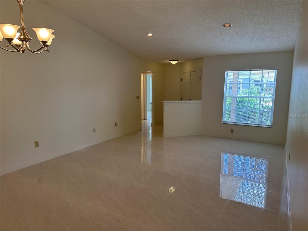 An empty room with light-colored tile flooring, a chandelier, and a window — 5915 TAYWOOD DRIVE, TAMPA, FL