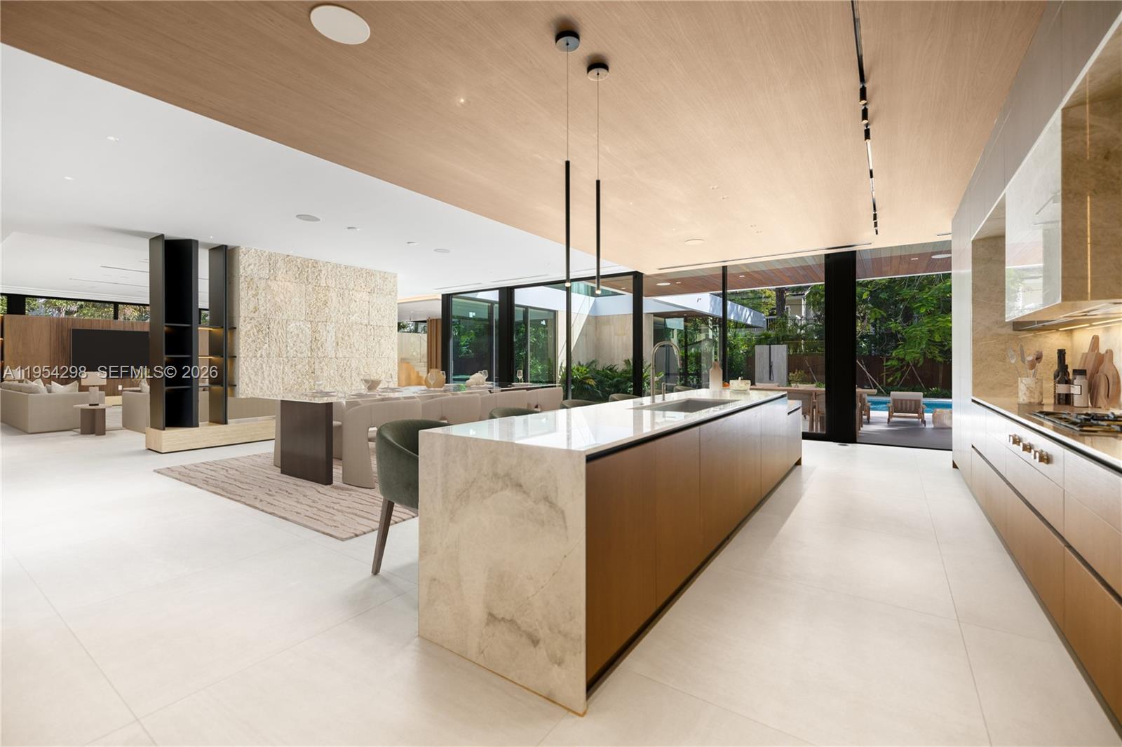 A modern open-plan kitchen and dining area features a stone island, wood ceiling, and patio — 3210 Coacoochee St, Miami FL 33133, MIAMI, FL