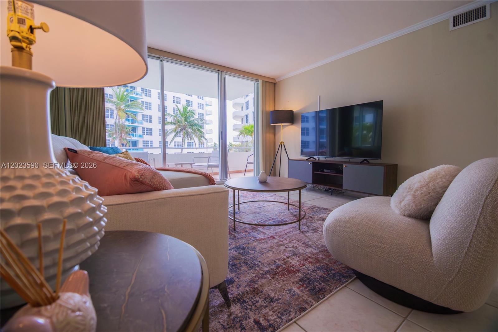A living room features a sofa, a round coffee table, and a television on a console — 5151 Collins Ave # 428, Miami Beach FL 33140, MIAMI BEACH, FL