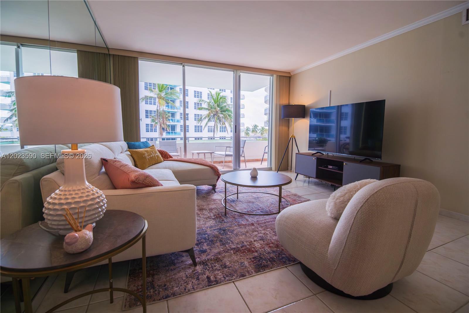 A living room features a sectional sofa, a round coffee table, and a balcony view — 5151 Collins Ave # 428, Miami Beach FL 33140, MIAMI BEACH, FL