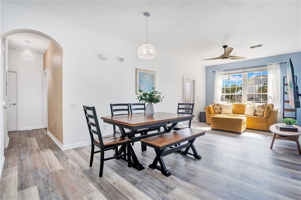 A dining area with a wooden table and bench opens into a living room space — 2307 BUTTERFLY PALM WAY UNIT 104, KISSIMMEE, FL