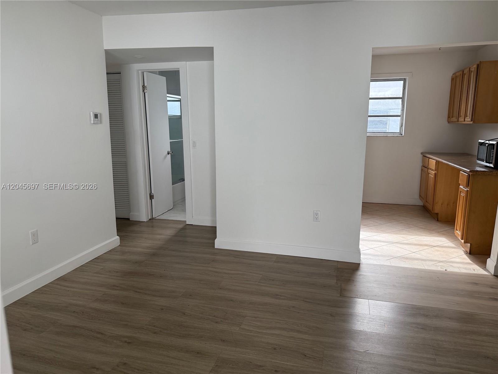 An interior view shows a living area with wood-look flooring leading to a tiled kitchen — 767 SW 9th St # 202, Miami FL 33130, MIAMI, FL