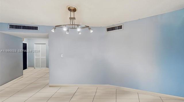 A room with light blue walls, tile flooring, and a modern circular chandelier — 1401 NE 191st St # D117, Miami FL 33179, MIAMI, FL