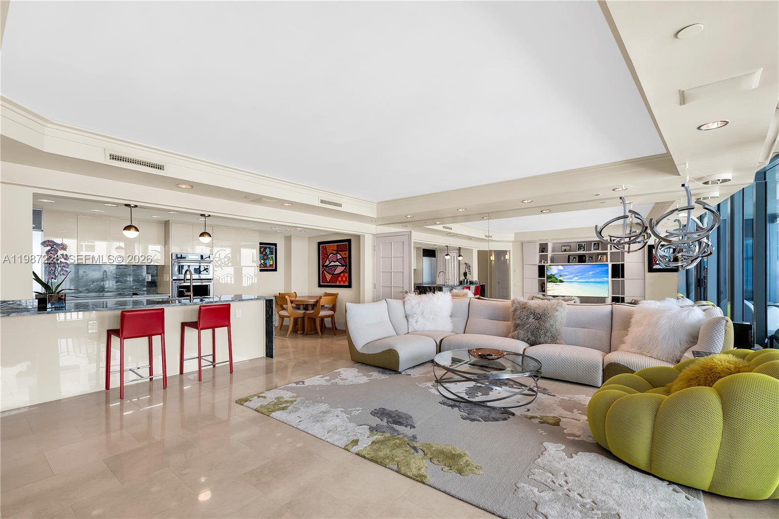 A modern open-concept living room features a kitchen island, white sectional sofa, and lime-green chair — 1500 Ocean Dr # 1005, Miami Beach FL 33139, MIAMI BEACH, FL