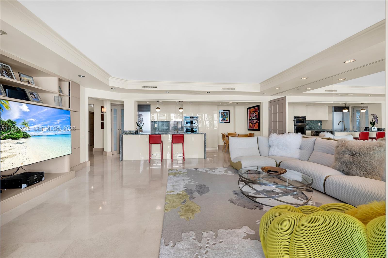 A modern living room features a large television, a kitchen island, and a sectional sofa — 1500 Ocean Dr # 1005, Miami Beach FL 33139, MIAMI BEACH, FL