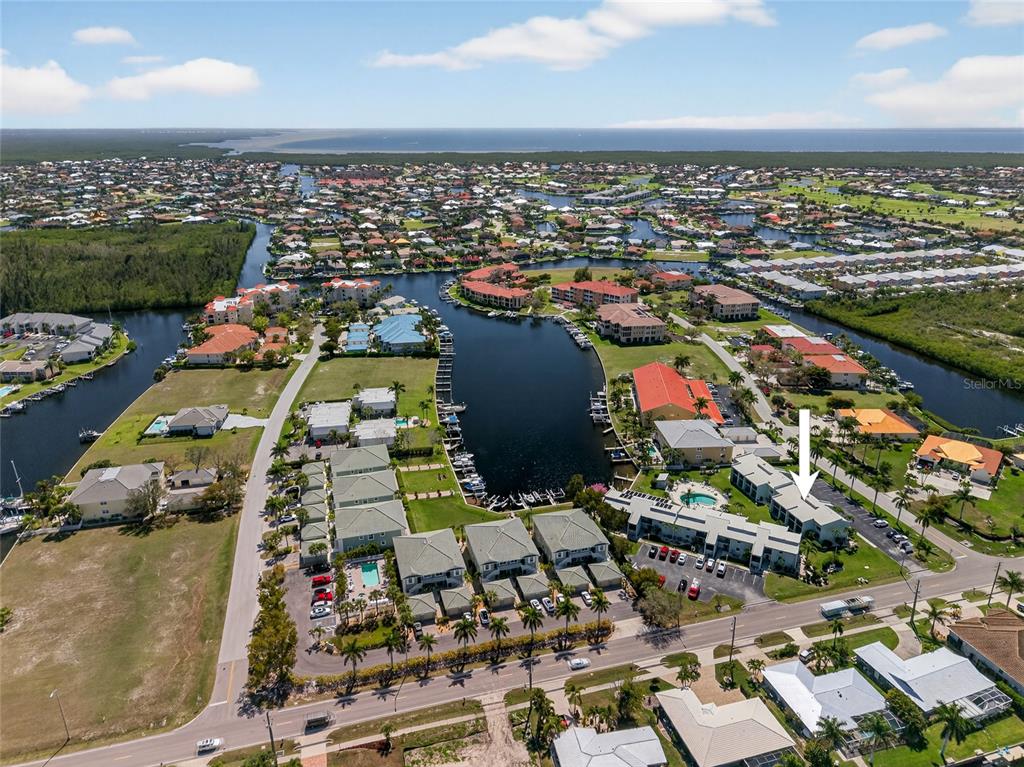 An aerial view shows a multi-story residential building with a parking lot and palm trees — 1461 AQUI ESTA DRIVE UNIT B3, PUNTA GORDA, FL